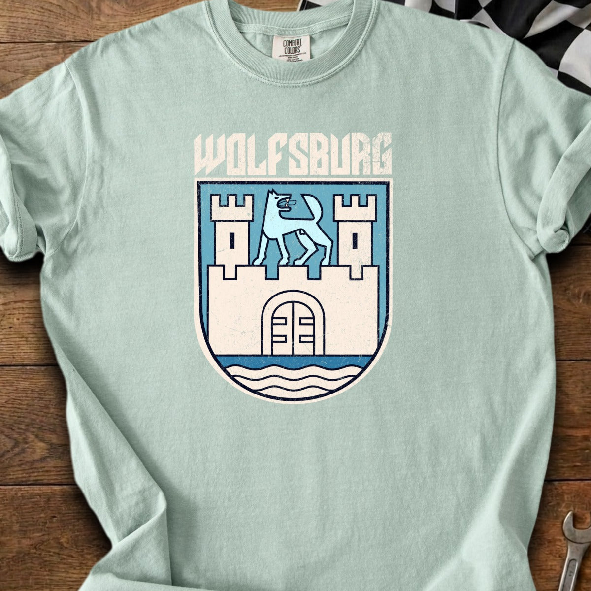 Light blue t-shirt with Wolfsburg crest featuring a wolf and castle.