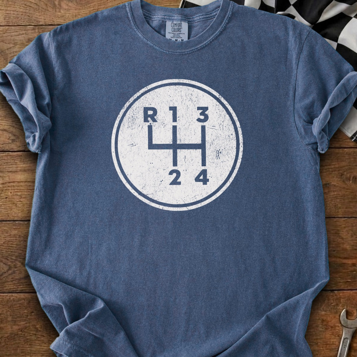 Blue t-shirt with a distressed white circle graphic of a manual transmission shift pattern.