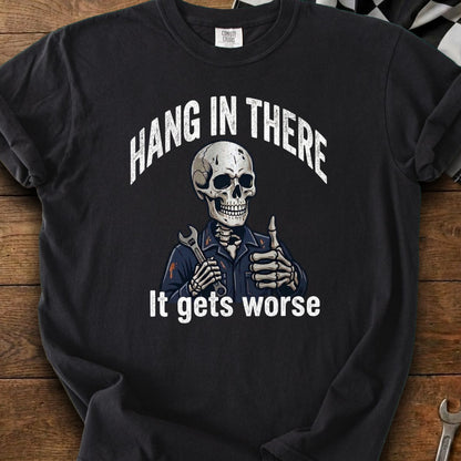 Black t-shirt with skeleton in mechanic's outfit holding a wrench and giving a thumbs up,text "Hang in there. It gets worse."