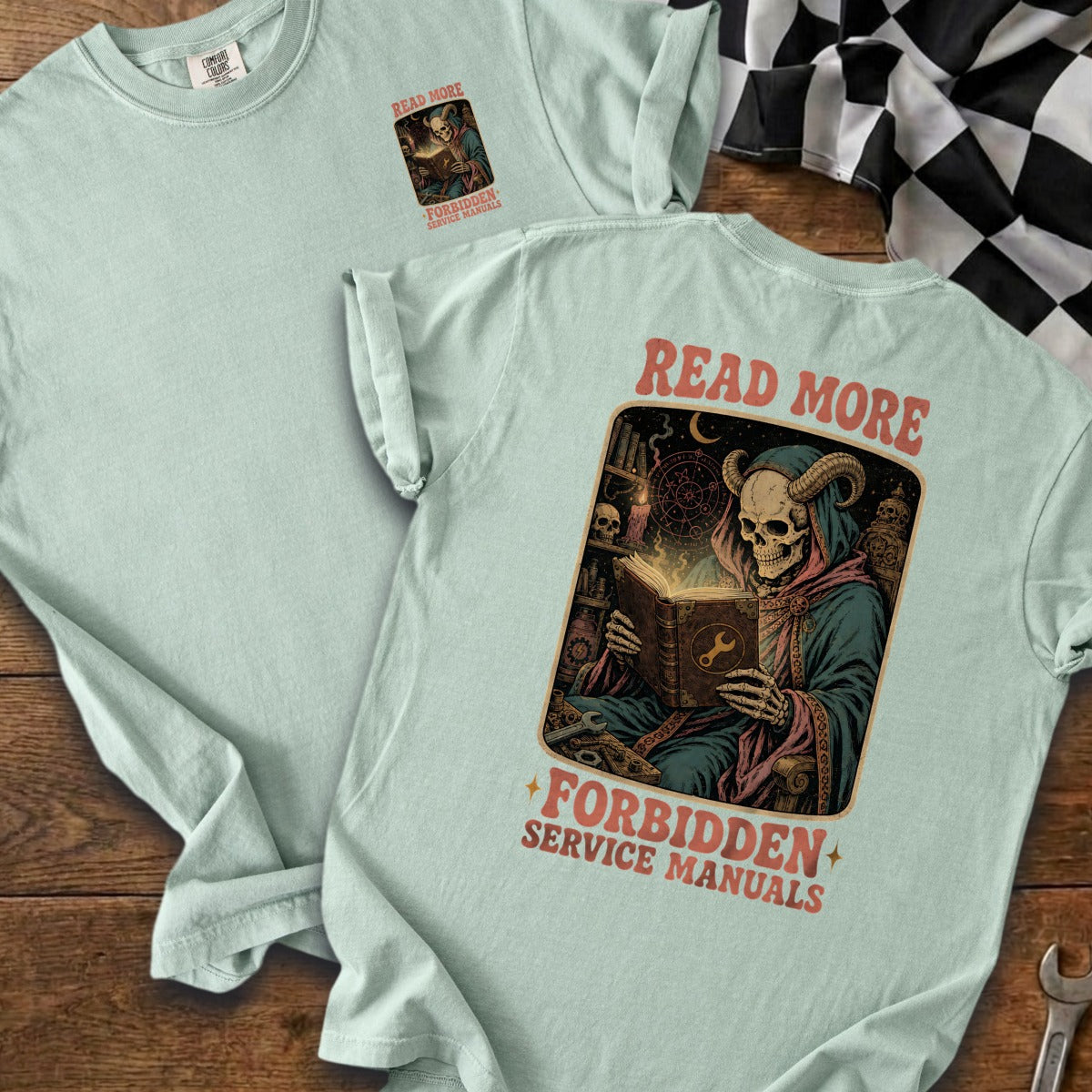 Light blue t-shirt with a skeleton in a hooded robe reading a book.