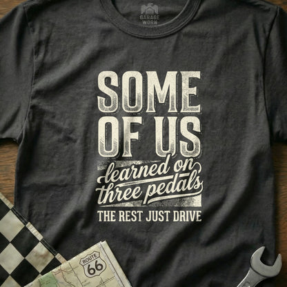Dark t-shirt with "SOME OF US learned on three pedals THE REST JUST DRIVE" text.