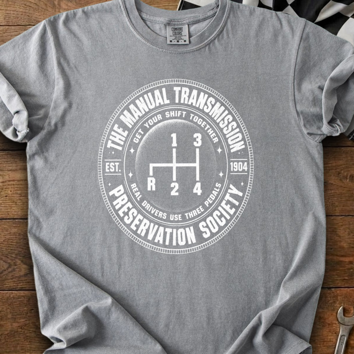 Gray t-shirt with white text and graphic of a manual transmission gear shift.
