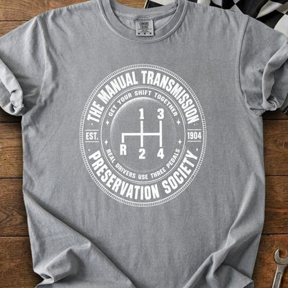 Gray t-shirt with white text and graphic of a manual transmission gear shift.