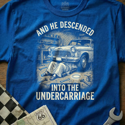 Blue t-shirt graphic of a person working on a car's undercarriage.
