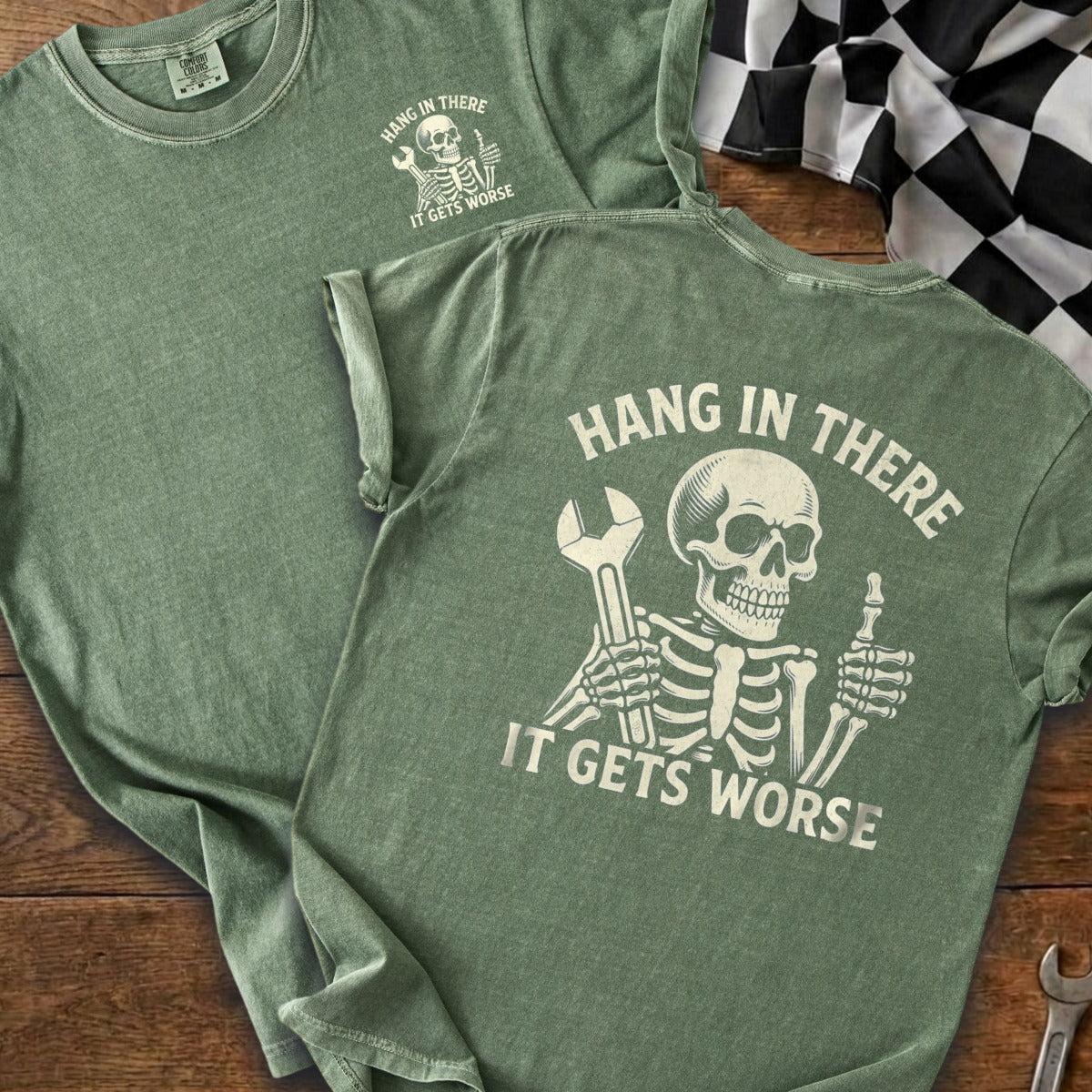 Green t-shirt with skeleton graphic holding a wrench and giving a thumbs up.