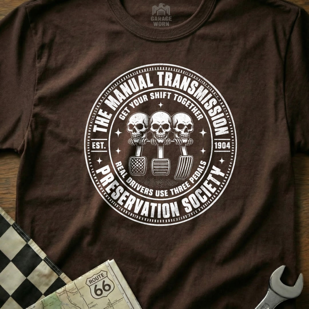 Brown t-shirt features "The Manual Transmission Preservation Society" circular graphic.