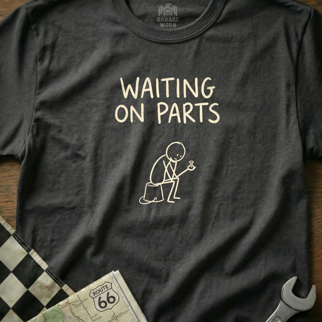 Dark gray t-shirt with "WAITING ON PARTS" text and a stick figure holding a bolt.