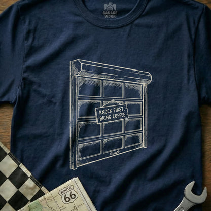 Navy t-shirt with a sketched garage door and "Knock First, Bring Coffee" sign.