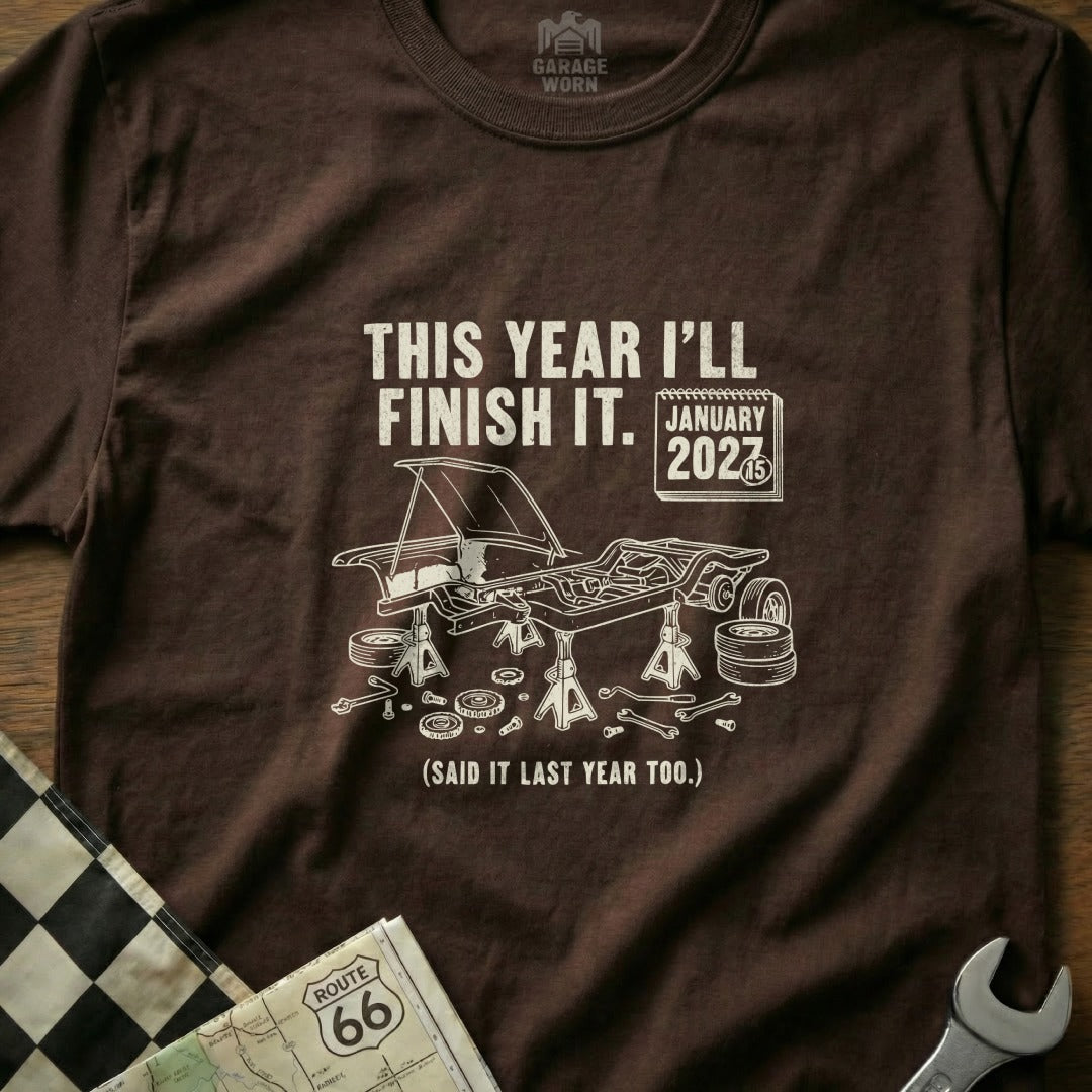 Brown t-shirt with text "THIS YEAR I'LL FINISH IT. JANUARY 2027 (SAID IT LAST YEAR TOO.)"