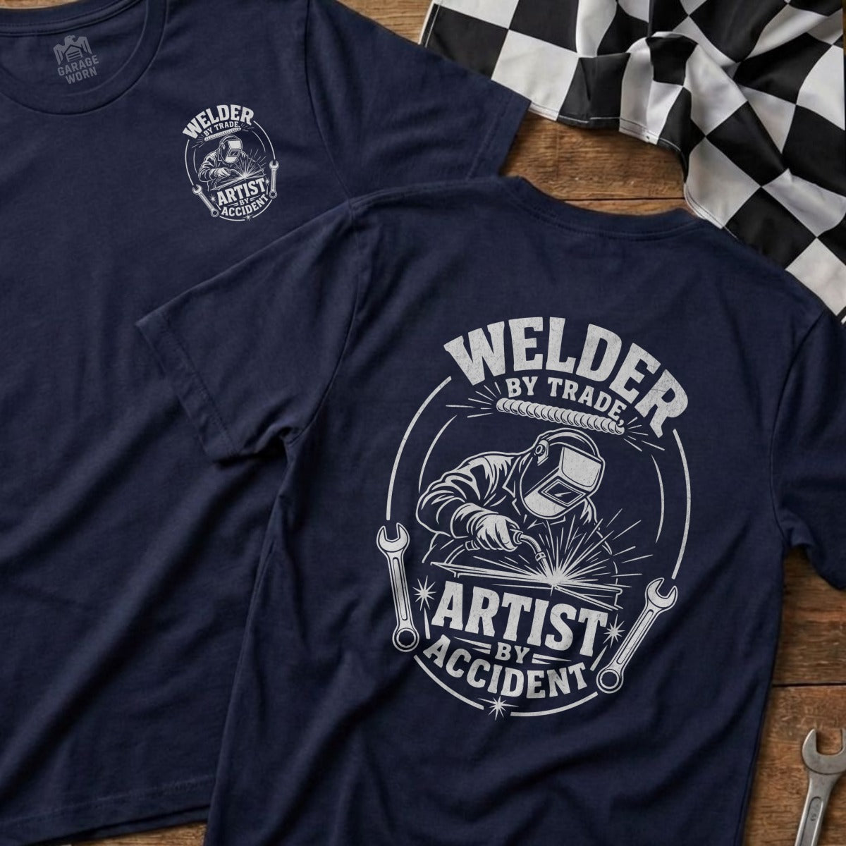 Navy t-shirt with "Welder by Trade, Artist by Accident" graphic.