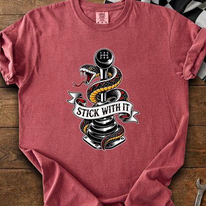 Snake coiled around a manual transmission stick shift with "STICK WITH IT" text.