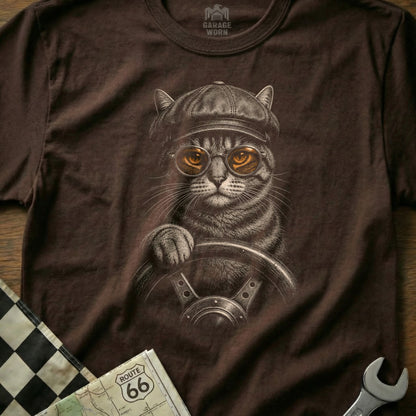 Tabby cat wearing cap and goggles drives with one paw on wheel.