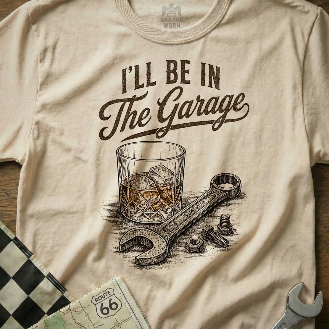 T-shirt with "I'll Be In The Garage" text, whiskey glass, wrench, and nuts.