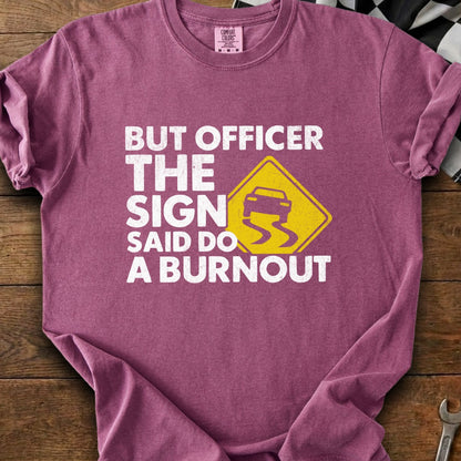 Maroon t-shirt with white text "BUT OFFICER THE SIGN SAID DO A BURNOUT" and a slippery car icon.