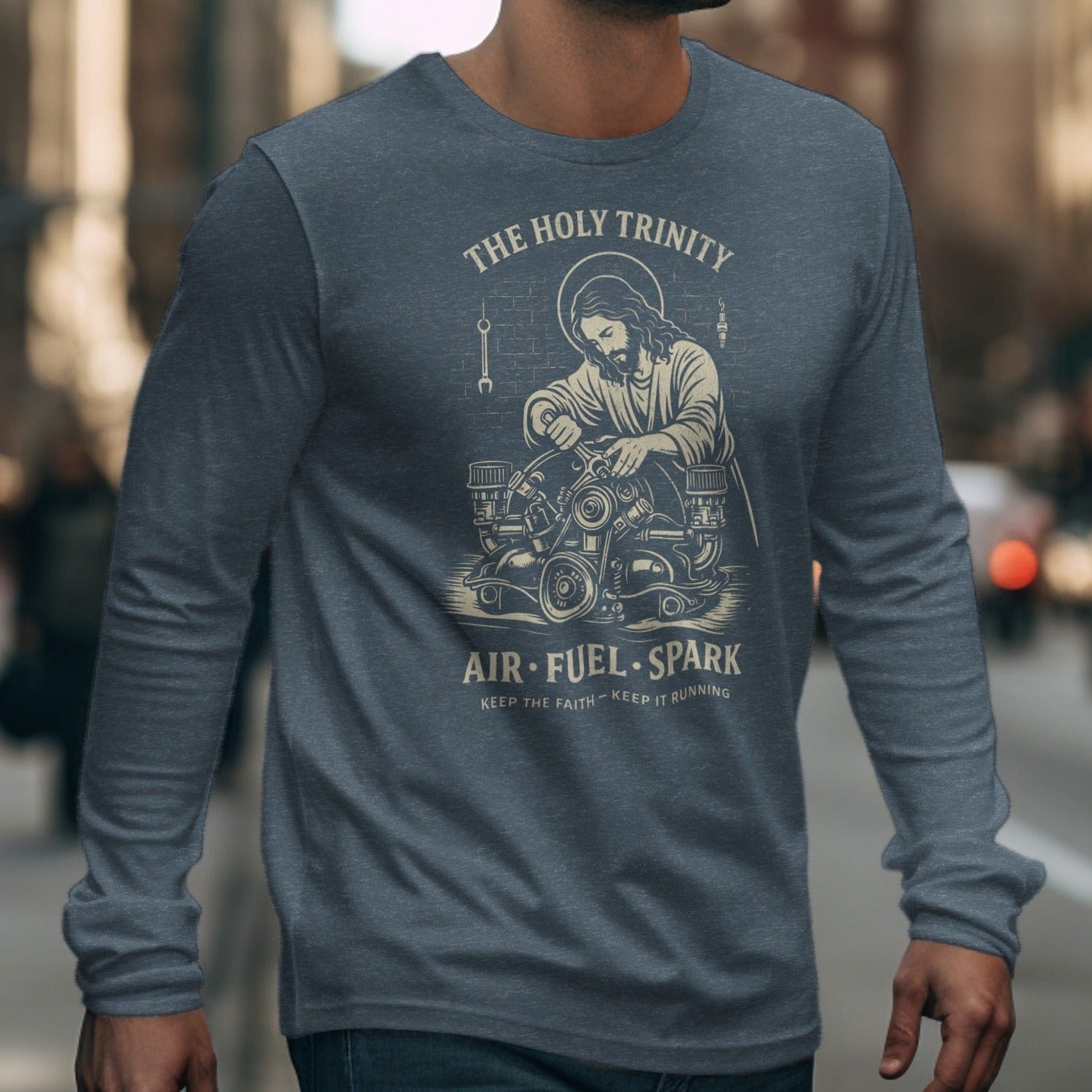 Long-sleeve shirt featuring Jesus working on an engine with text "The Holy Trinity Air Fuel Spark".