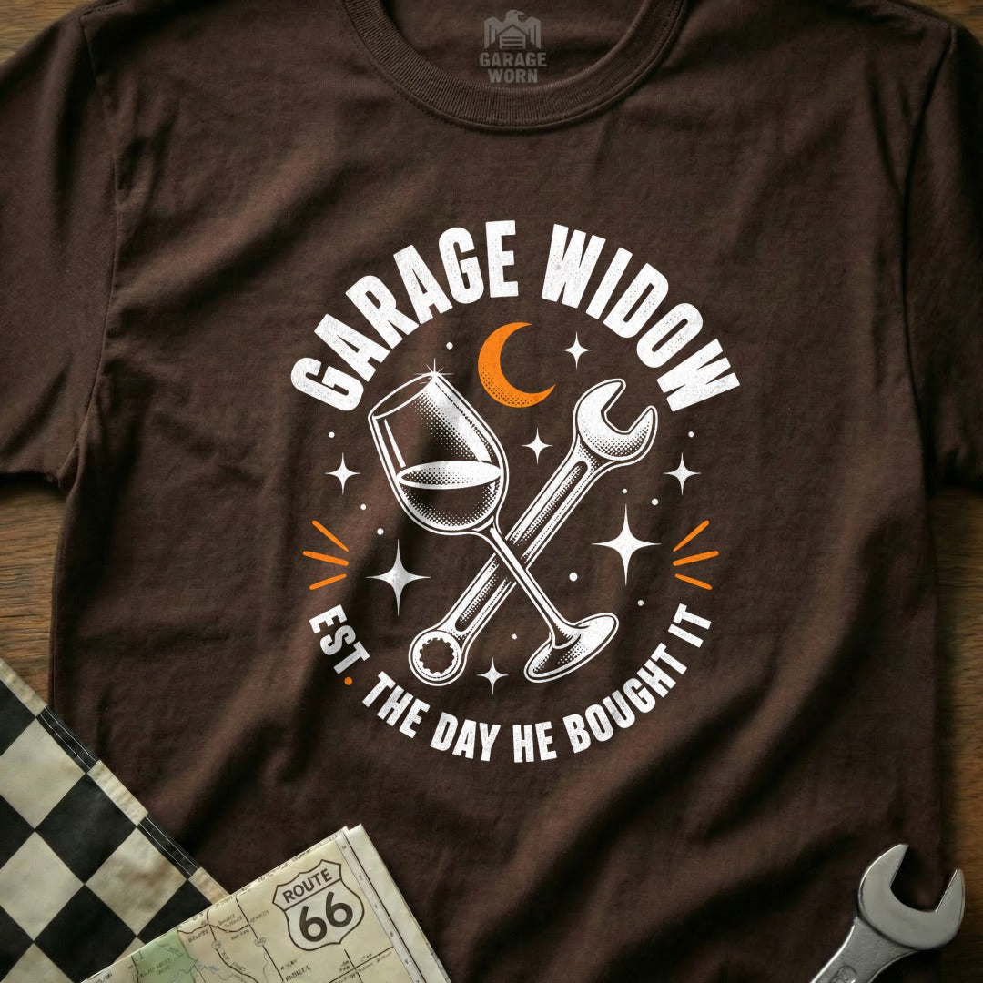 Brown t-shirt with "Garage Widow Est. The Day He Bought It" text, wine glass, and wrench graphic.