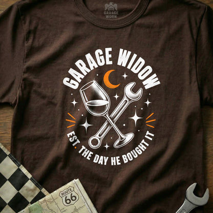 Brown t-shirt with "Garage Widow Est. The Day He Bought It" text, wine glass, and wrench graphic.