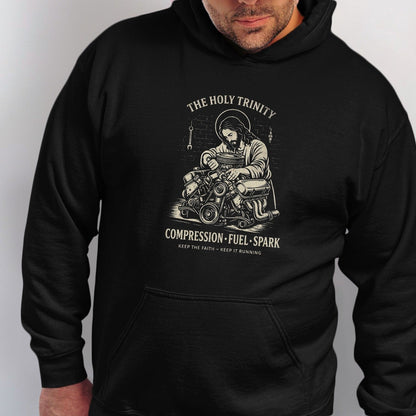 Black hoodie with graphic of Jesus working on an engine, "The Holy Trinity" text.