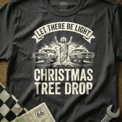 Jesus with arms raised between two classic cars on a "Christmas Tree Drop" t-shirt.