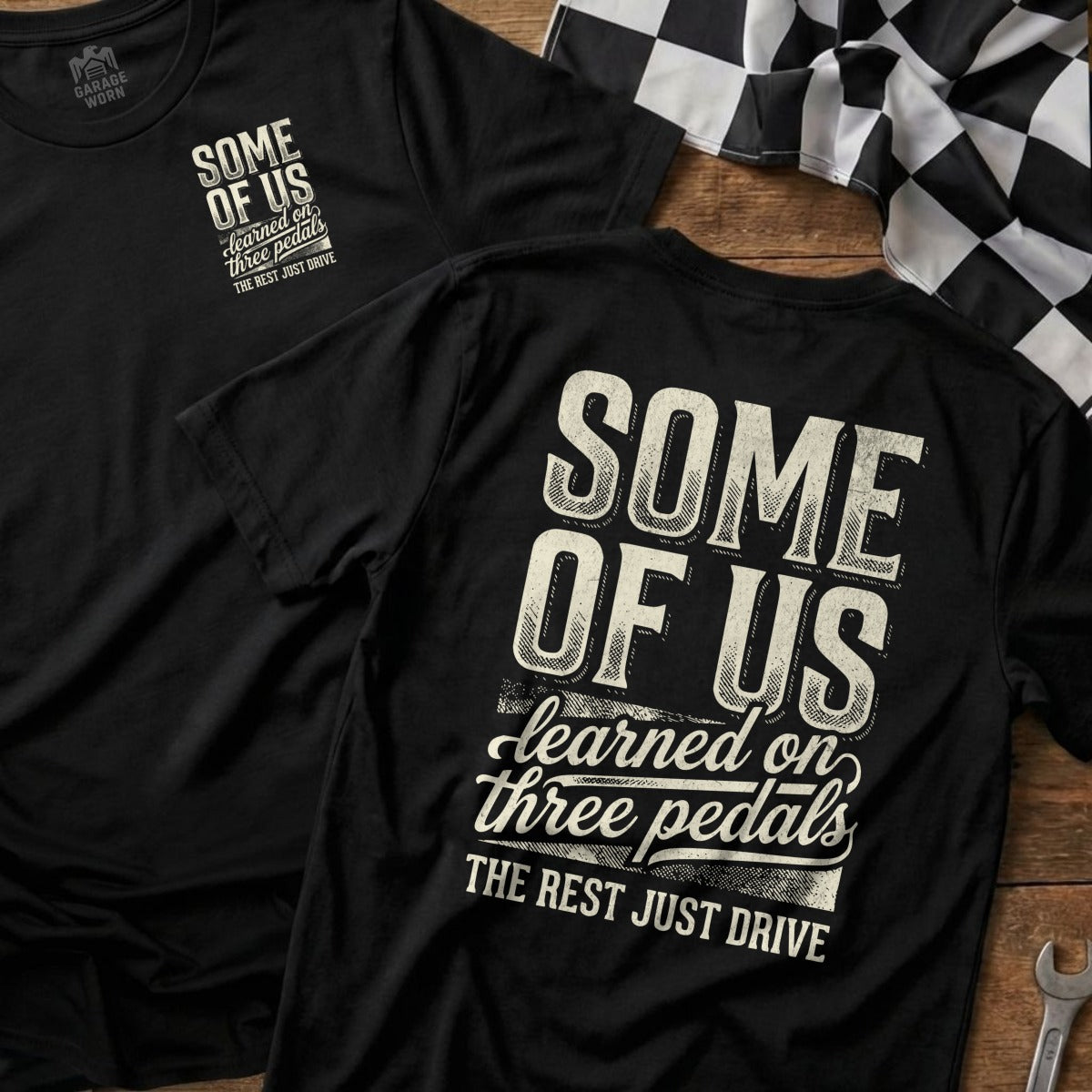 Two t-shirts with the text "Some of us learned on three pedals, the rest just drive."