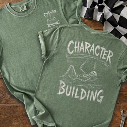Green t-shirt with "Character Building" graphic of skeleton working on car.