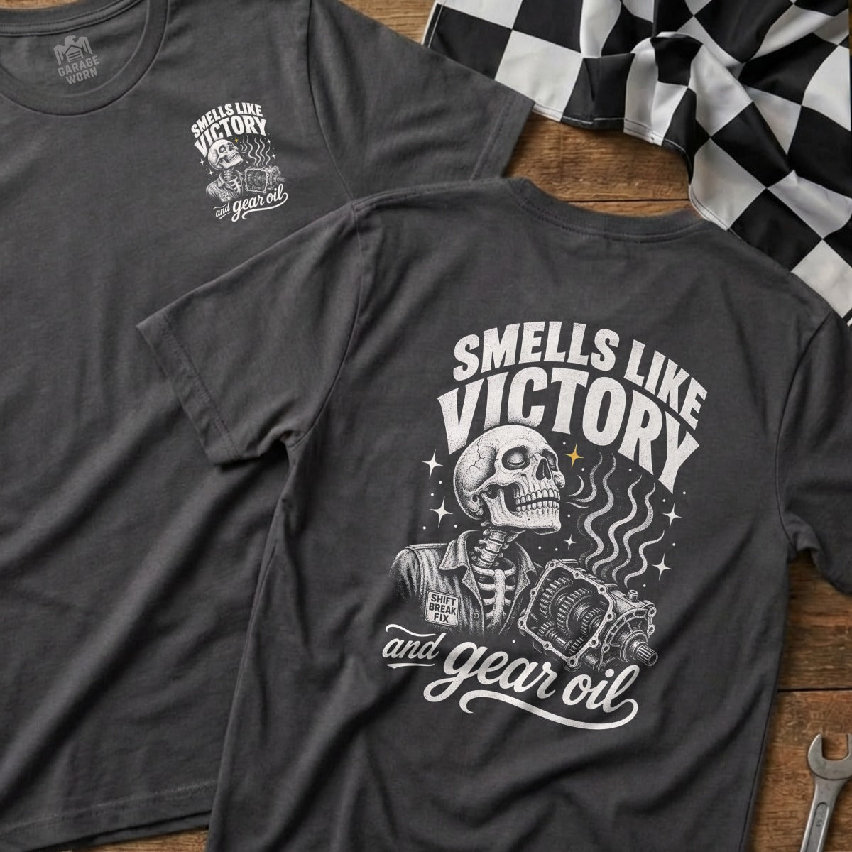 Dark gray t-shirt with "Smells Like Victory and Gear Oil" graphic of a skeleton holding a transmission.