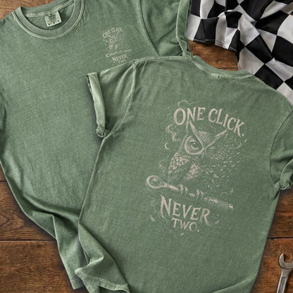 Green t-shirt with owl graphic and text "ONE CLICK. NEVER TWO."