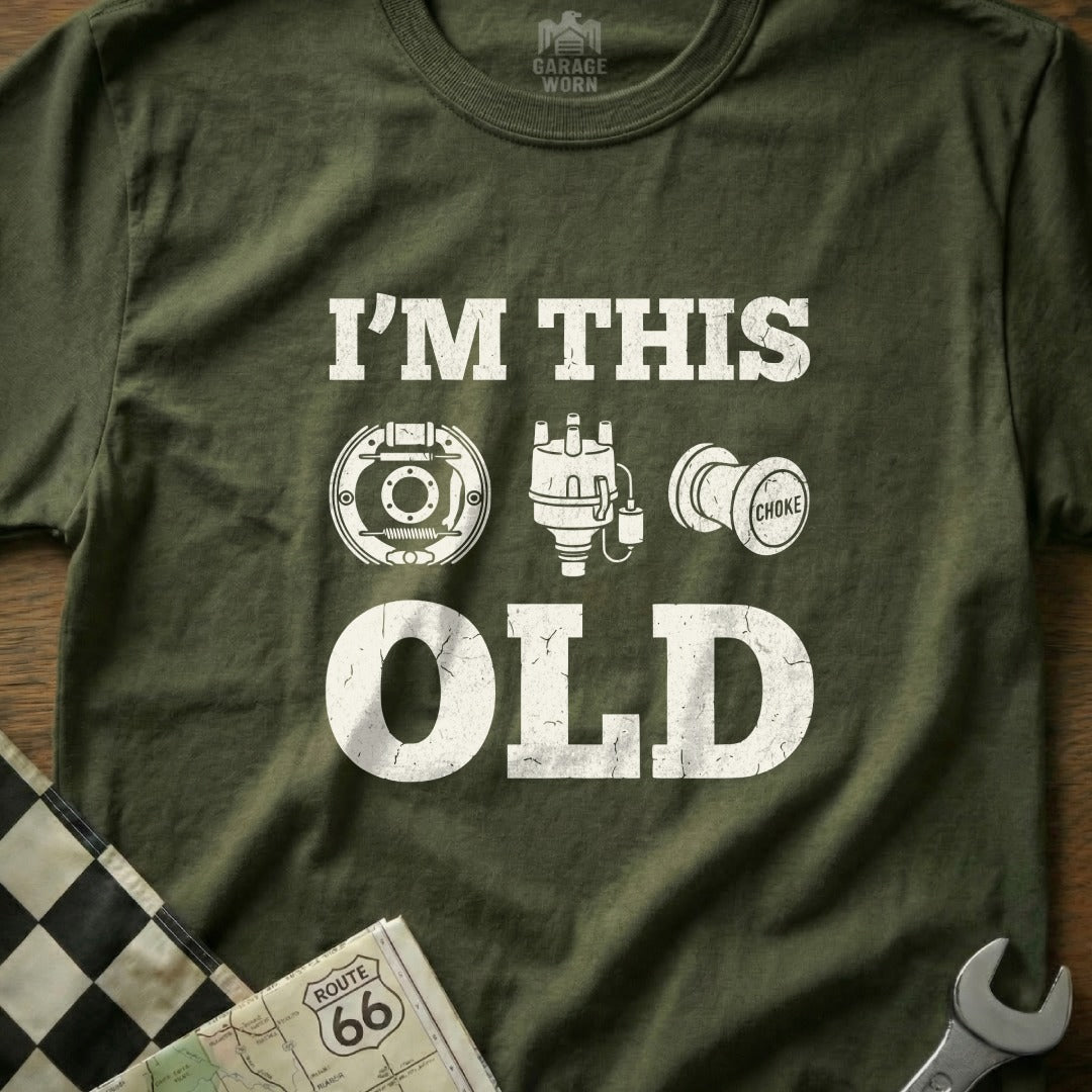 Olive green t-shirt with white text "I'M THIS OLD" and car part graphics.