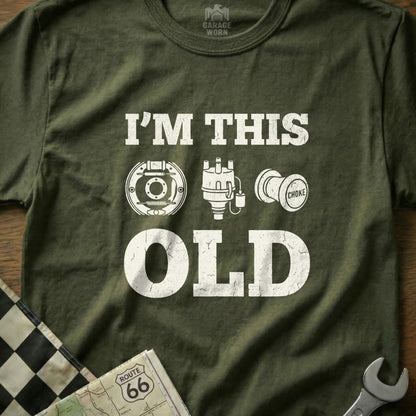 Olive green t-shirt with white text "I'M THIS OLD" and car part graphics.