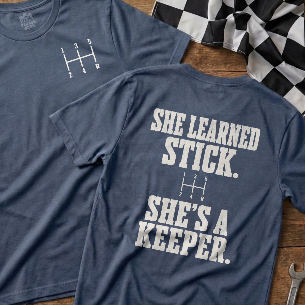 Navy t-shirt with a gear shift graphic and "SHE LEARNED STICK. SHE'S A KEEPER." text.