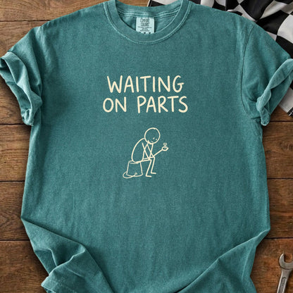 Teal t-shirt with "WAITING ON PARTS" text and a stick figure holding a screw.