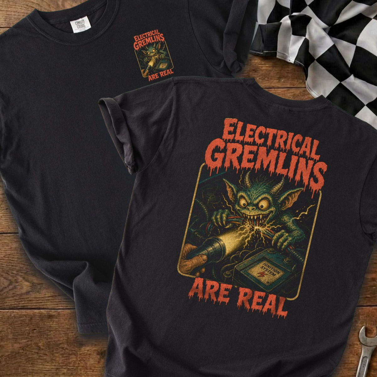 Black t-shirt with a graphic of a gremlin shorting wires, "Electrical Gremlins Are Real" text.