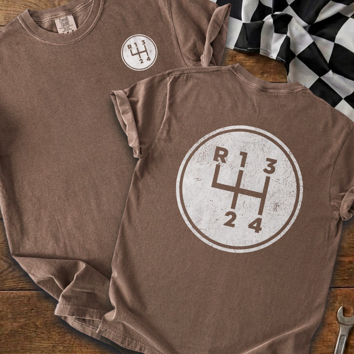 Brown t-shirt with a graphic of a manual transmission shift pattern in a circle.