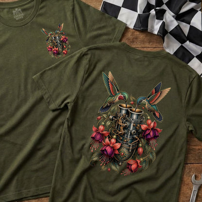 Two hummingbirds feed from a metallic carburetor surrounded by vibrant fuchsia flowers.