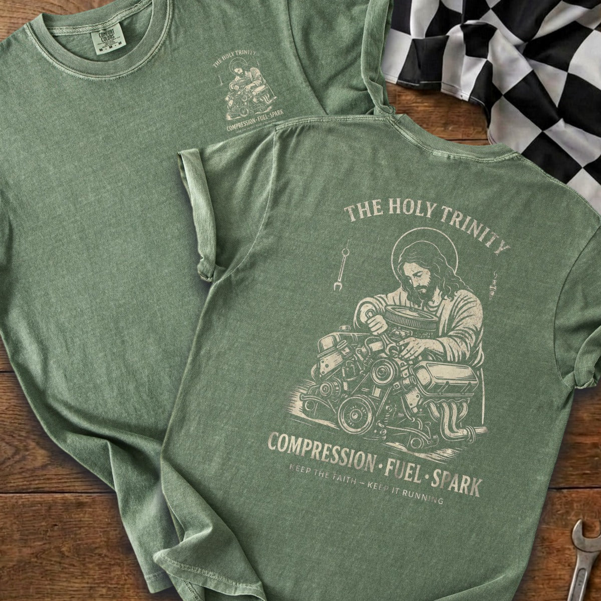 Green t-shirt with graphic of Jesus working on an engine. "The Holy Trinity" and "Compression. Fuel. Spark." printed.