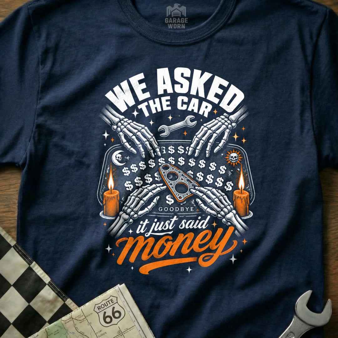 Dark t-shirt with skeleton hands on Ouija board, "WE ASKED THE CAR it just said money."