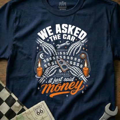 Dark t-shirt with skeleton hands on Ouija board, "WE ASKED THE CAR it just said money."