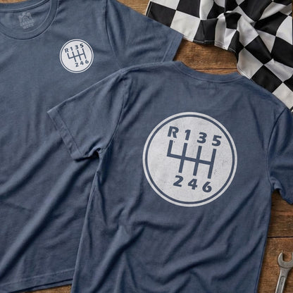 Two dark blue t-shirts with a white circular manual transmission shift pattern graphic.