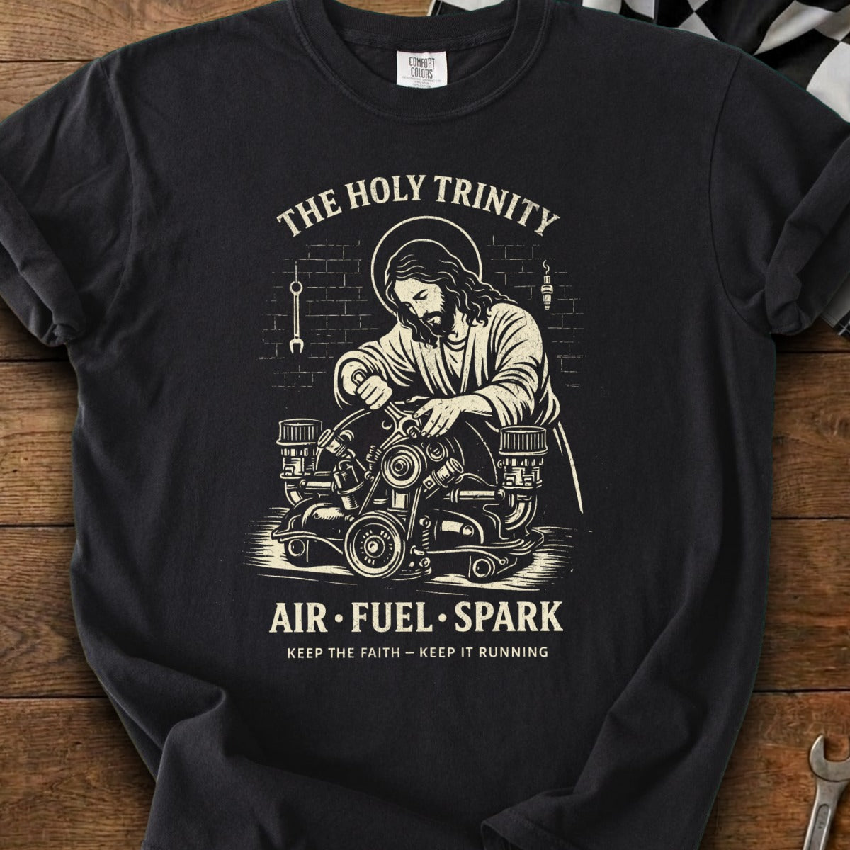 Jesus works on an engine with text "The Holy Trinity Air Fuel Spark Keep the Faith Keep It Running."