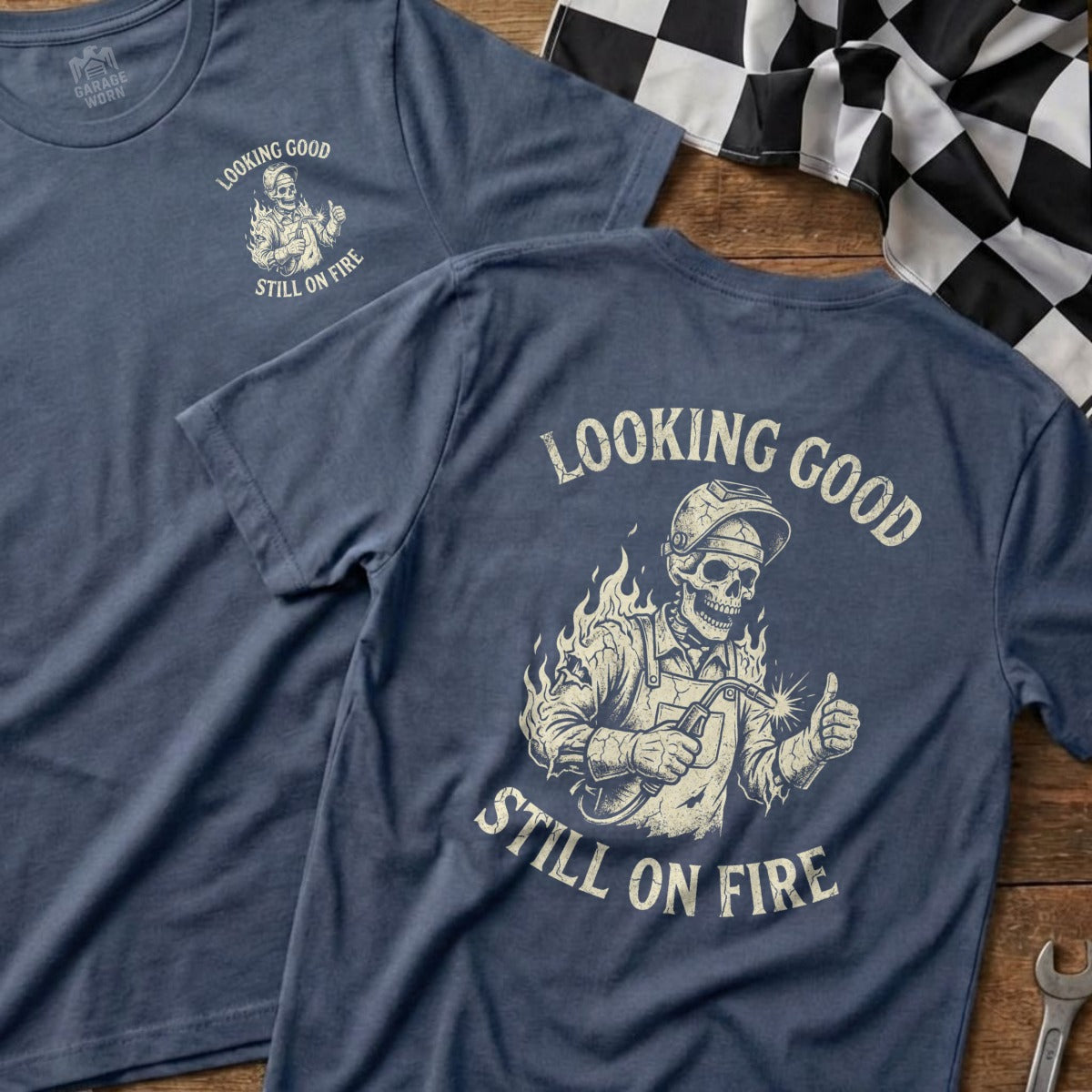 Blue t-shirt with skeleton welder graphic and "Looking Good Still On Fire" text.