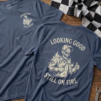 Blue t-shirt with skeleton welder graphic and "Looking Good Still On Fire" text.