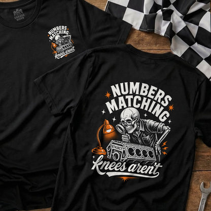 Black t-shirt with skeleton inspecting engine block: "Numbers Matching Knees Aren't".