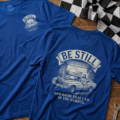Blue t-shirt with Jesus driving a classic car and text: "Be Still and Know That I Am in the Garage."