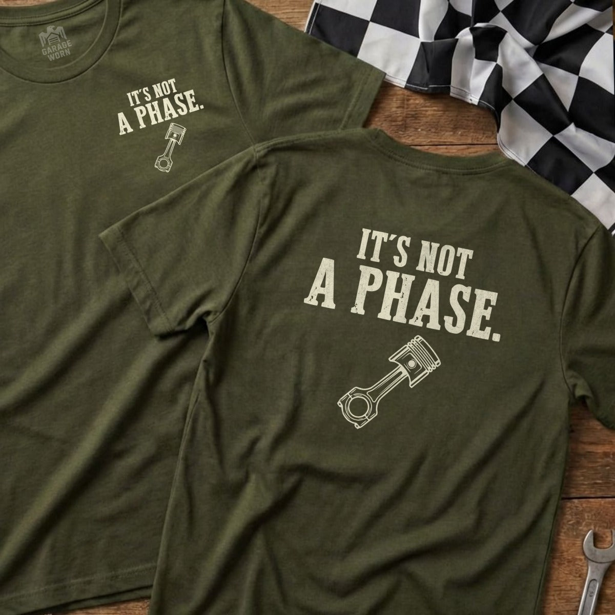 Two olive green t-shirts with a piston graphic and "It's Not A Phase." text.