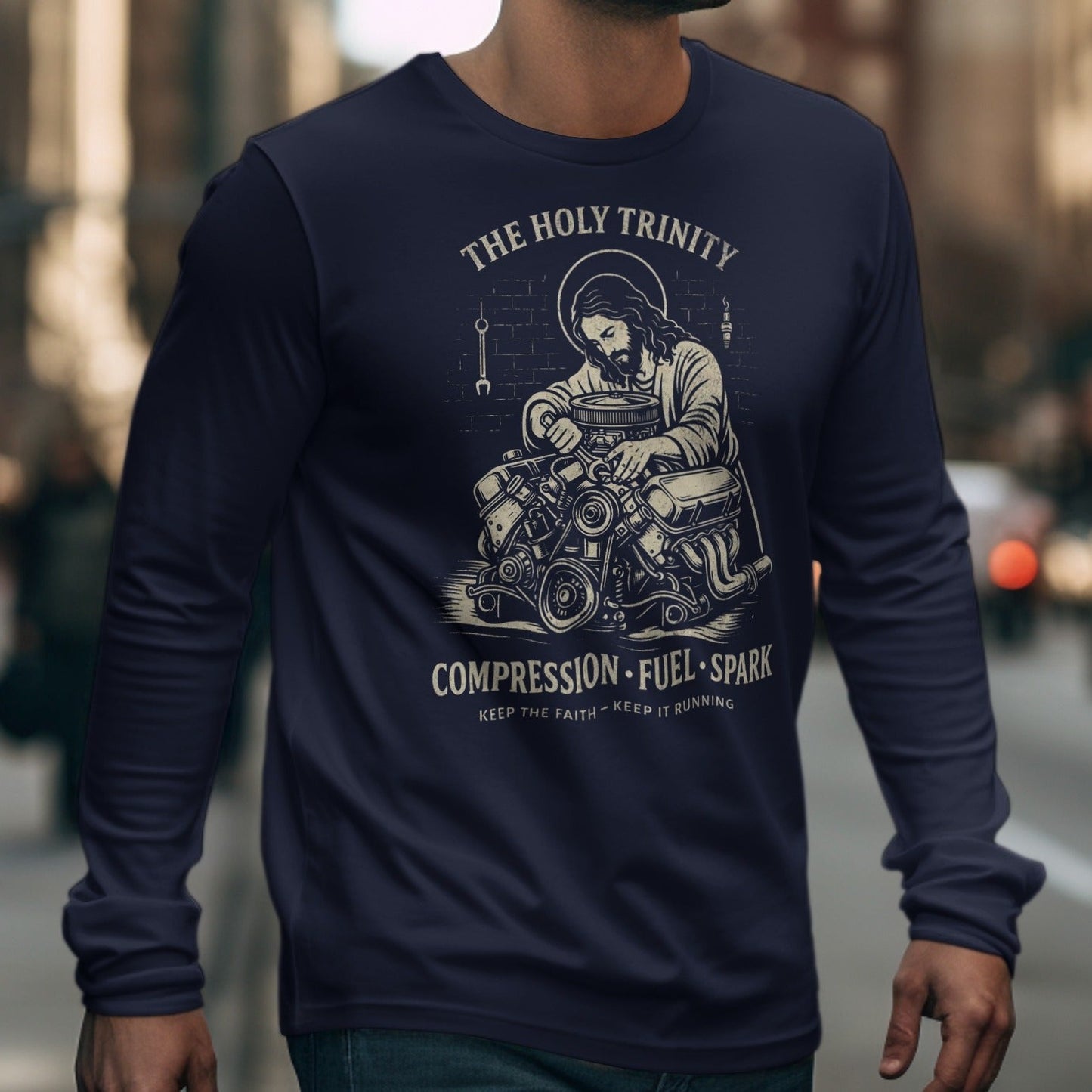 Long sleeve shirt with Jesus working on an engine, text "THE HOLY TRINITY".