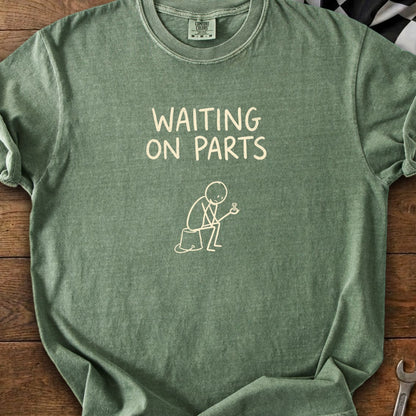 Green t-shirt graphic with text "WAITING ON PARTS" and a stick figure holding a gear.