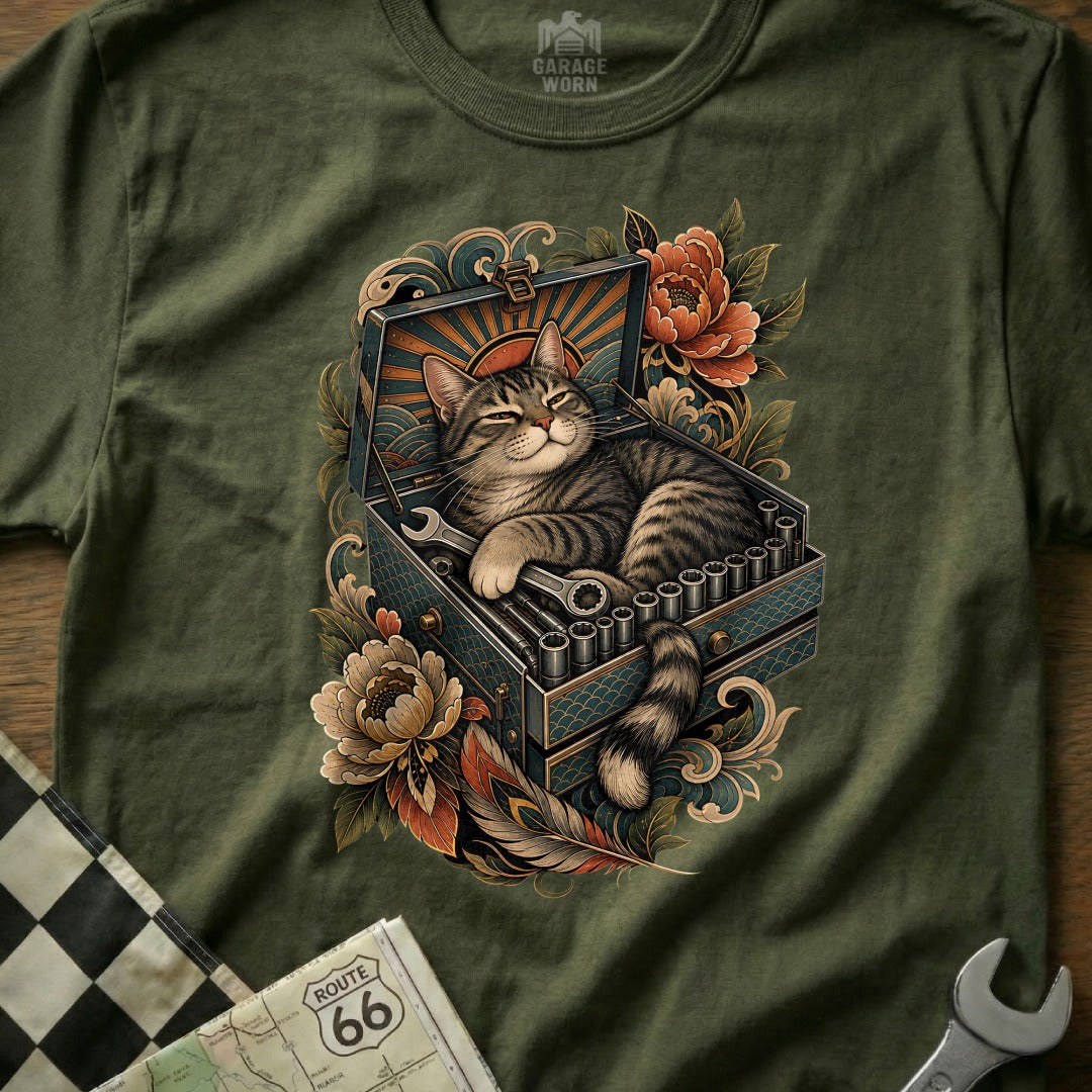 Tabby cat sleeping in an open toolbox with wrenches and flowers.