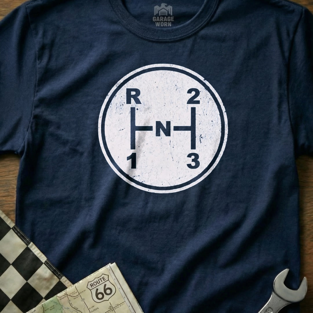 Navy t-shirt with a white vintage-style, five-speed manual transmission shift pattern graphic.