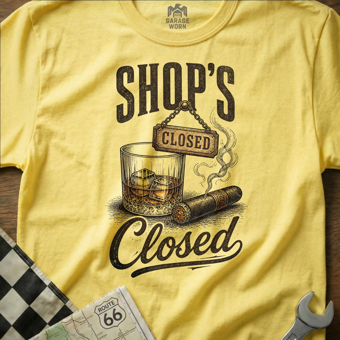 Yellow t-shirt with "SHOP'S CLOSED" text, whiskey glass, cigar, and checkered flag.