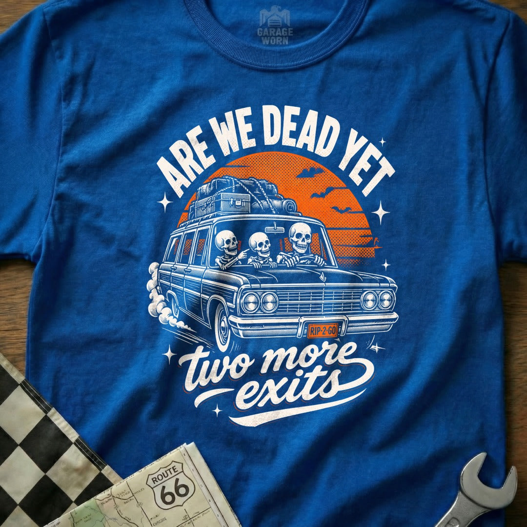 Blue t-shirt with skeletons in a car, "ARE WE DEAD YET" and "two more exits" text.